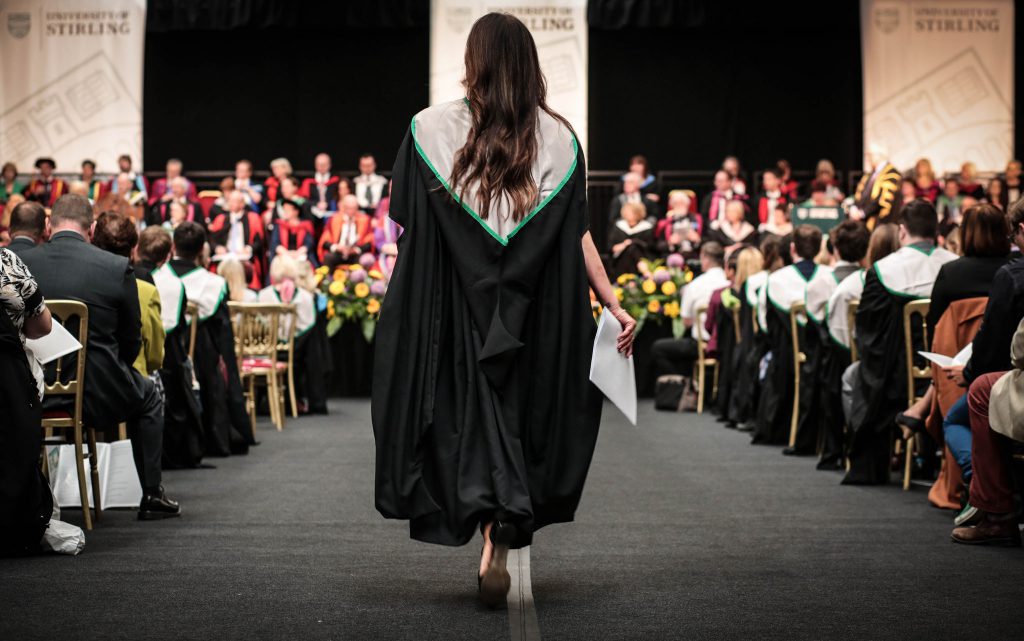 Woman walking down aisle after Graduation at University of Stirling