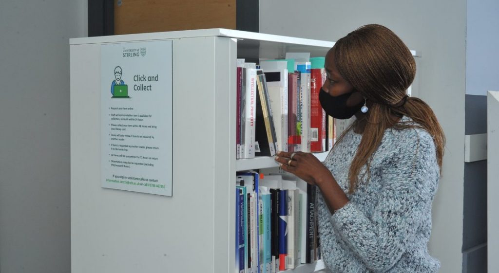 Woman searching library click and collect shelf