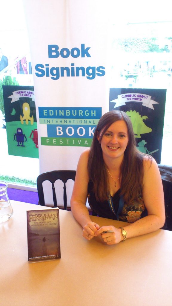 Woman smiling at book signing, with her book beside her. 