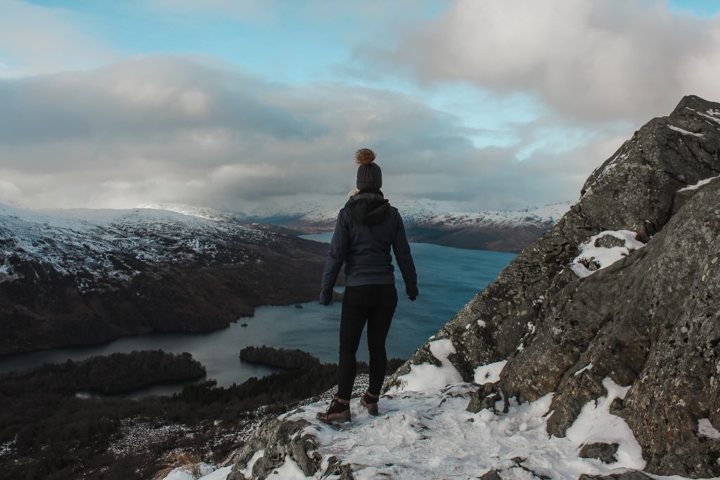 Woman at the top of mountain overlooking a loch. 