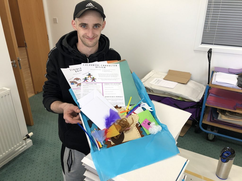 A man holding a Craft Kids box with arts and crafts materials inside.